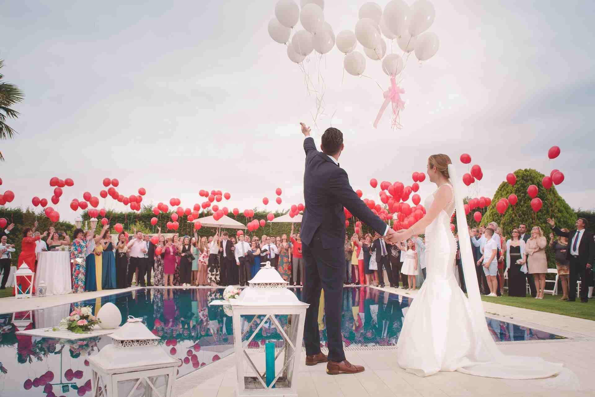 A couple releasing balloons at their poolside wedding