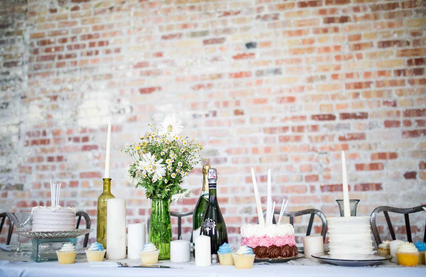 A brunch table set with champagne, cakes, and cupcakes.