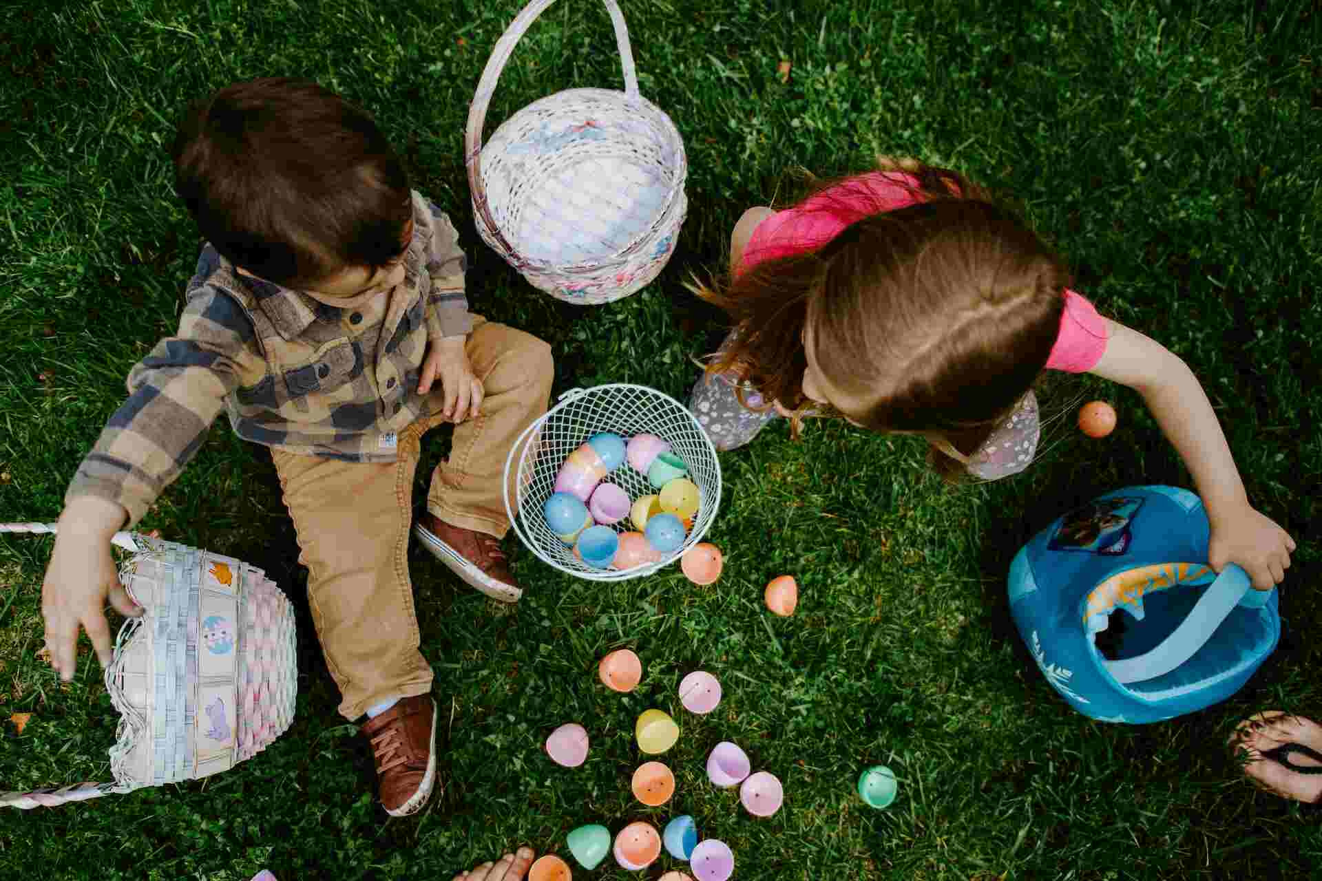 A girl and a boy are sitting outside with Easter eggs and Easter baskets