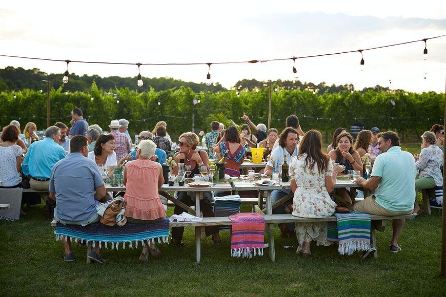 Dozens of family members sitting at picnic tables.