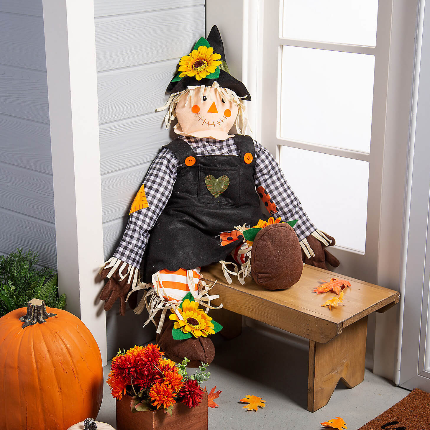 fall decorations pumpkins, scarecrows, sunflowers on bench
