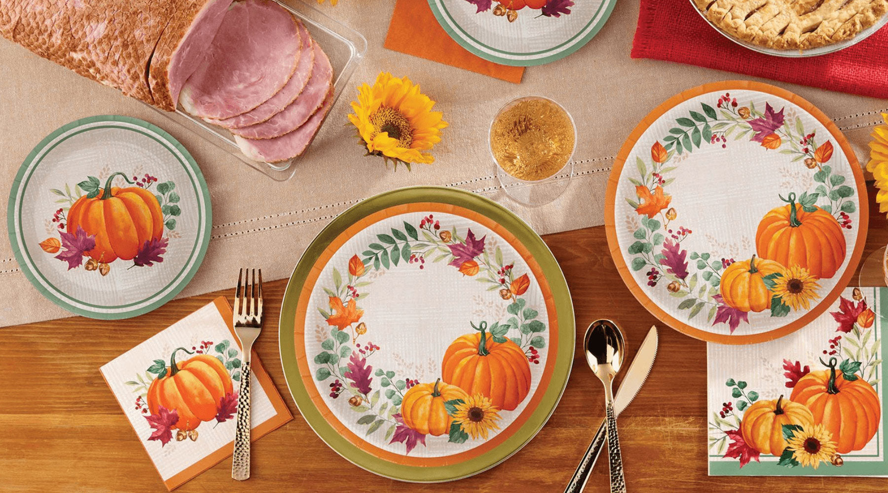 Table setting with decorative plates featuring pumpkins and autumn designs, accompanied by silverware and napkins.